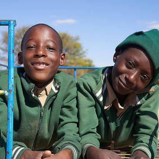 Zwei elfjährige Jungen aus Simbabwe sitzen auf einem Klettergerüst