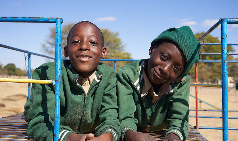 Zwei elfjährige Jungen aus Simbabwe sitzen auf einem Klettergerüst