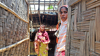 Zwei Frauen stehen in ihrem zerstörten Haus in Bangladesch