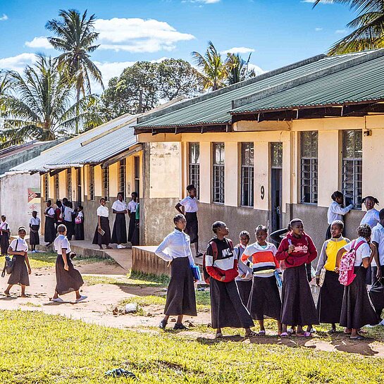 Mädchen und Jungen stehen vor einer Schule, die Plan International in Mosambik gebaut hat