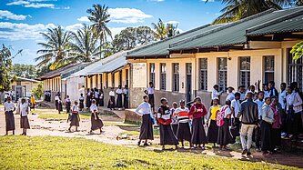 Mädchen und Jungen stehen vor einer Schule, die Plan International in Mosambik gebaut hat