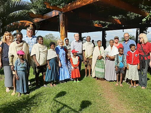 Unser Treffen am See. Pat:innen und Kinder stehen unter Holz-Pavillion.
