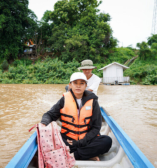 Mit dem Boot überquert Pheakdey den Fluss, um ihre Schüler:innen auf der abgelegenen Insel zu unterrichten Pheakdey auf Boot im Fluss