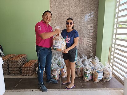 Ein Mann übergibt einer Frau eine Nahrungsmittelration