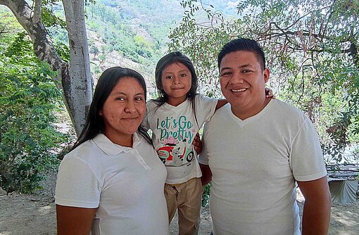 Eine Frau und ein Mann tragen zusammen ein kleines Mädchen auf ihren Schultern