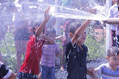 Kinder spielen an dem neuen Brunnen in ihrer Gemeinde