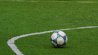 Fußball auf grünem Rasen mit weißer Markierung