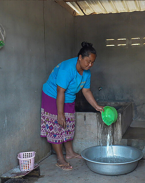 Nulai vor der neuen Toilette und Wascheinrichtung ihres Hauses