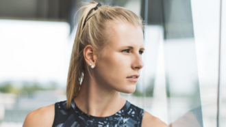 Sportlerin Verena Mayr schaut aus einem Fenster, in dem sie sich spiegelt.