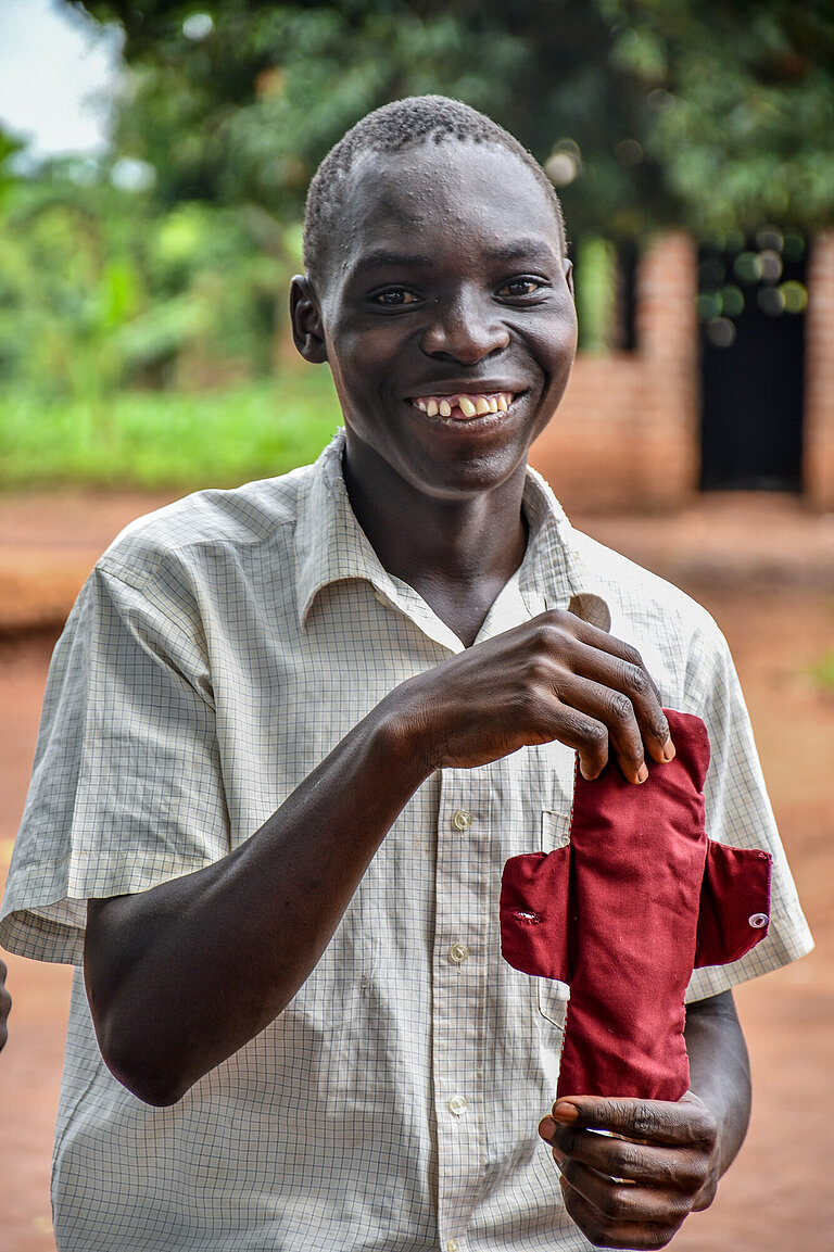 Ein Junge zeigt eine selbstgenähte Binde hoch und lächelt
