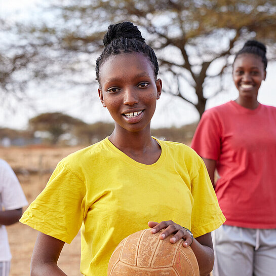 Drei junge Frauen draußen mit einem Basketball