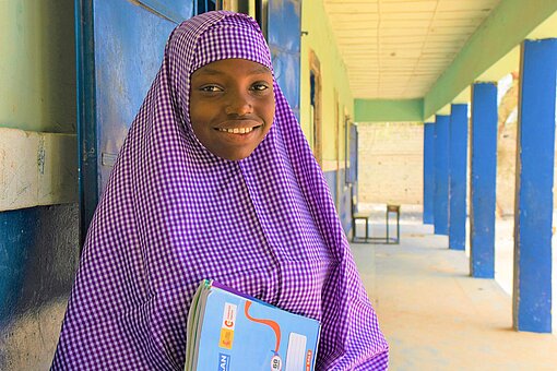 Hadiza (14) will unbedingt die Schule abschließen Ein Mädchen lacht im Foyer einer Schule