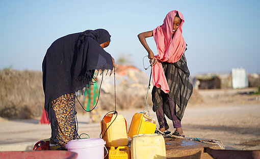 Wenn die Wassertransporter nicht kommen, müssen die Camp-Bewohner:innen Wasser aus dem Brunnen holen – das ist aber nicht sauber. Barwaaqo und ihre Freundin holen gemeinsam Wasser aus dem Brunnen.