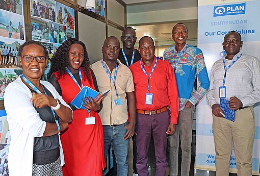 Die Fachleute von Plan International Südsudan in der Hauptstadt Juba Männer und Frauen schauen in die Kamera