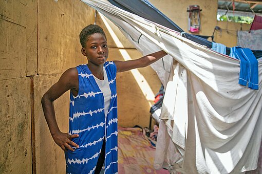 Nur durch Laken von anderen Personen getrennt schläft Caroline* (15) in einer Notunterkunft außerhalb von Port-au-Prince Ein Mädchen zeigt ihren Schlafplatz