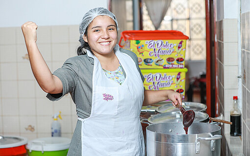 Eine junge Frau steht begeistert von ihrem Erfolg in der Küche