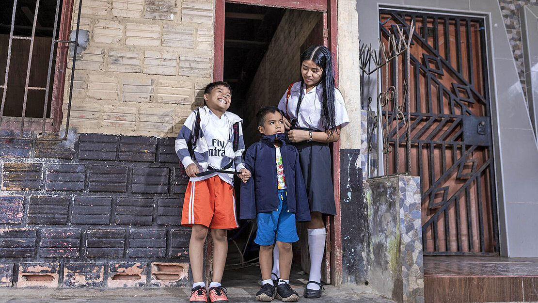Ein Mädchen und zwei Jungen vor einem Haus