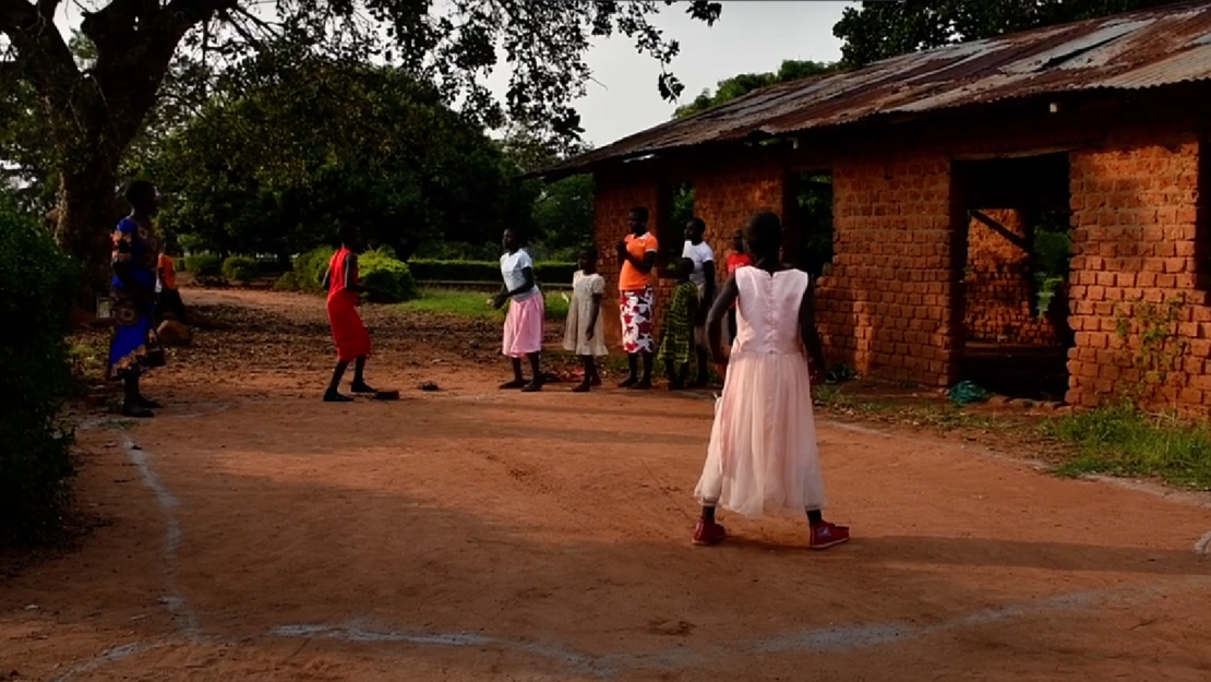 Kinder aus Uganda spielen draußen ein Wurf- und Laufspiel