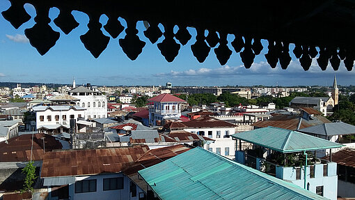Bis an die Mauern der UNESCO-Weltkulturerbe-Stadt Stone Town reichen die Neubausiedlungen heran. Blick über die Dächer der Siedlungen in Stone Town.