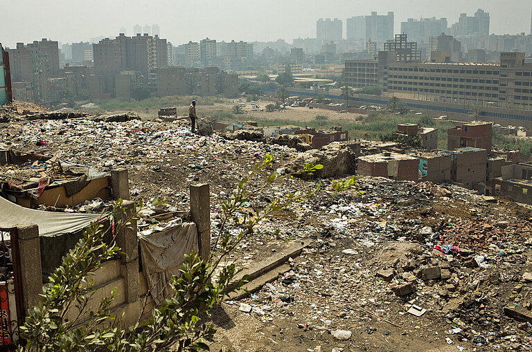 Blick über eine Müllhalde mit Häusern am Rande von Kairo