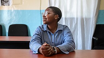 Ein junges Mädchen mit Brille schaut zur Seite und lächelt