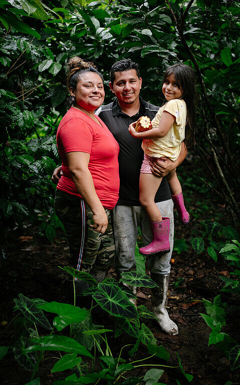 Yenny steht gemeinsam mit ihrem Mann und ihrer jüngsten Tochter vor ihrem Zuhause in einer ländlichen Gemeinde in Ecuador.