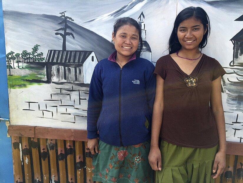 Urmila (right) and her friend stand in front of their temporary school, which currently supports the 41 children