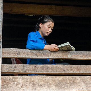 Ein vietnamesisches Mädchen sitzt am Fenster und liest ein Buch