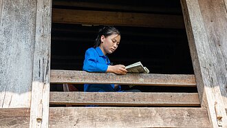 Ein vietnamesisches Mädchen sitzt am Fenster und liest ein Buch