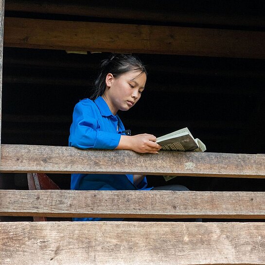 Ein vietnamesisches Mädchen sitzt am Fenster und liest ein Buch