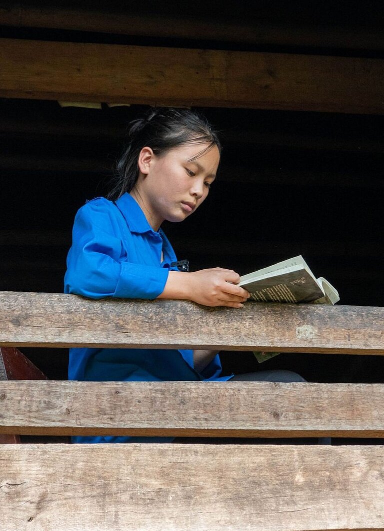 Ein vietnamesisches Mädchen sitzt am Fenster und liest ein Buch