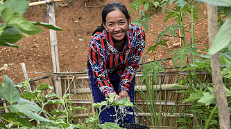 Win, eine junge Frau aus Laos, gießt ihren Gemüsegarten. 
