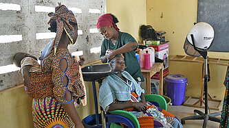 Ein Frau frisiert die Haare einer Kundin
