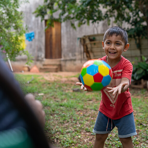 Ein kleiner Junge fängt einen bunten Ball