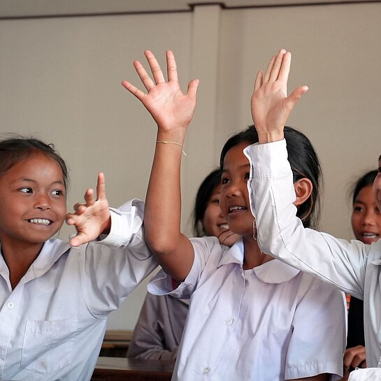 Drei Mädchen sitzen fröhlich im modernen Klassenzimmer einer Schule in Laos
