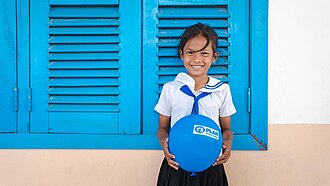 Ein Plan-Patenkind hält einen blauen Luftballon in der Hand