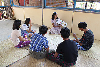 Jugendliche sprechen über eine Zeichnung, die eine junge Frau ihnen zeigt