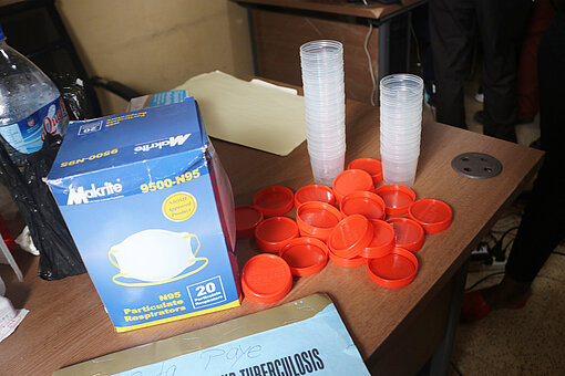 Tuberkulose in Liberia Eine Packung mit medizinischen Masken und gestapelte Plastikbecher, neben denen die dazugehörigen Deckel liege, stehen auf einem Tisch