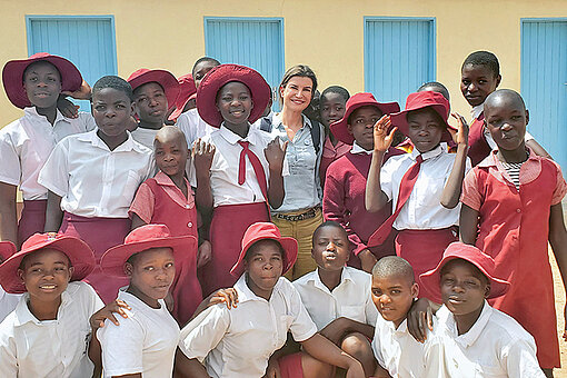 Julia Selle, Geschäftsführerin der Stiftung Hilfe mit Plan, im Plan-Programmgebiet in Simbabwe Eine Frau steht zwischen Schülerinnen in Simbabwe