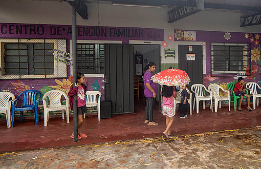 Ein flaches Gebäude steht im Regen und Kinder laufen davor