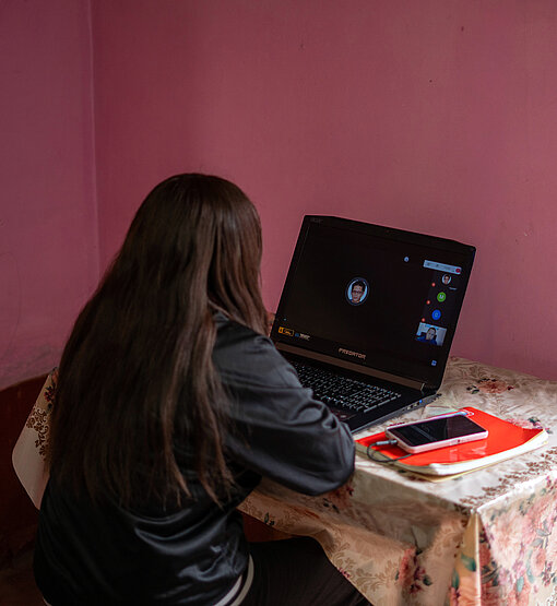 Aitana sitzt in ihrem Zuhause und lernt am Laptop für ihr Studium
