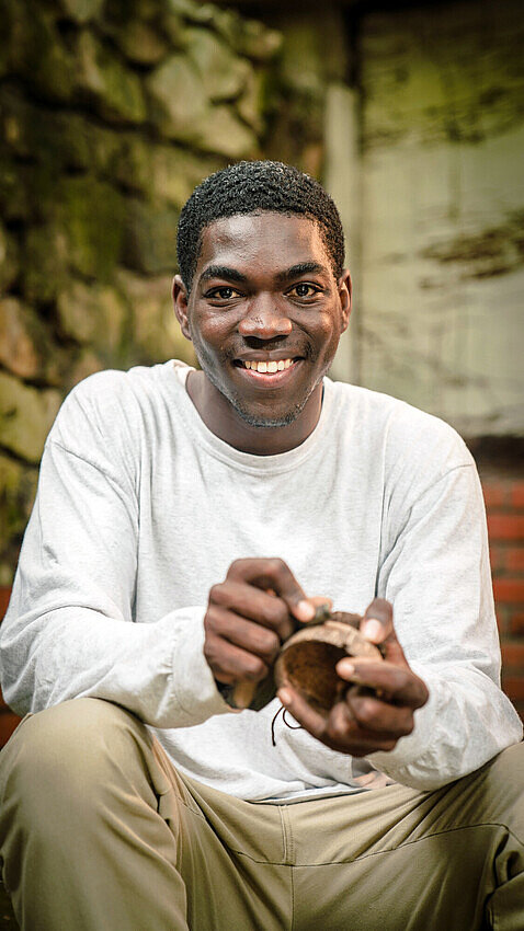 Ein junger Kunsthandwerker arbeitet konzentriert an der Fertigung einer hölzernen Schale in seiner Werkstatt