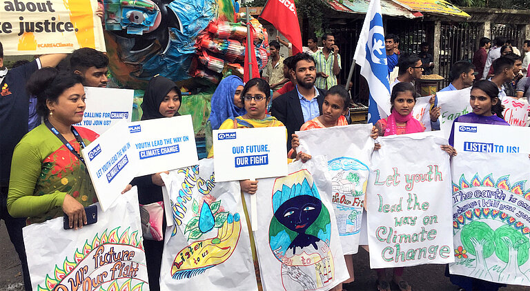 Junge Erwachsene halten Schilder auf einer Klimademonstration.
