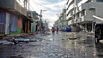 Nach dem Abzug eines Wirbelsturms liegen Trümmer und Schrott in einer Straße zwischen Häusern