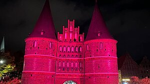 Das Holstentor in Lübeck wird im Dunkeln pink erleuchtet.