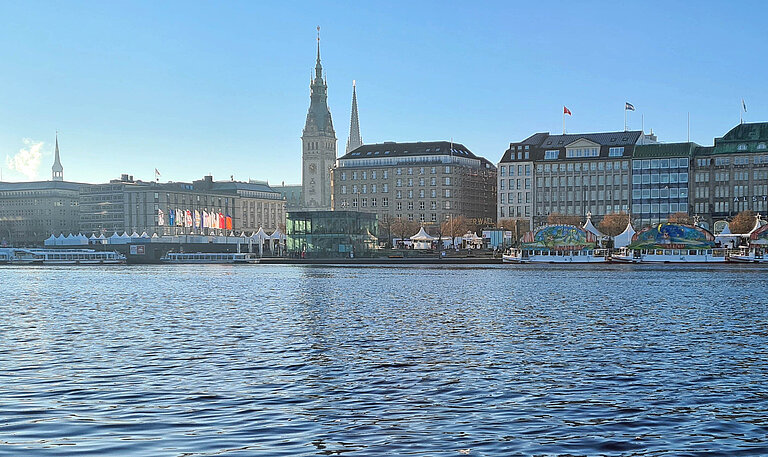 Blick auf die Hamburger Innenstadt mit Rathaus sowie Binnenalster, auf der mehrere Ausflugsschiffe zu sehen sind