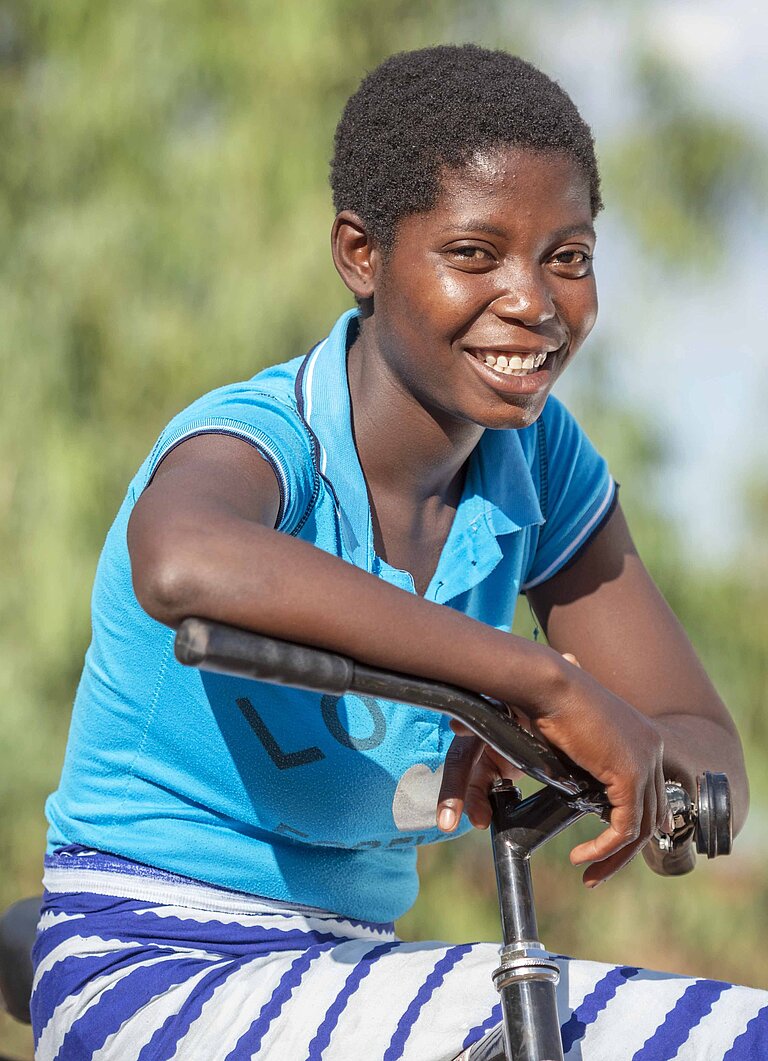 Eine junge Frau lacht auf ihrem Fahrrad sitzend