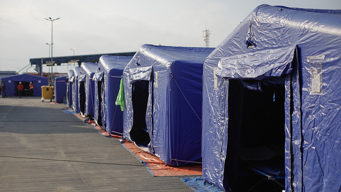 Mehrere blaue Zelte stehen in einer Reihe nebeneinander