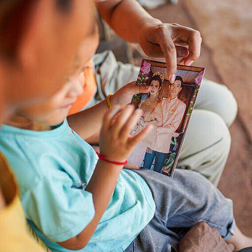 Ein kleines Kind hält eine Hochzeitsbild in den Händen
