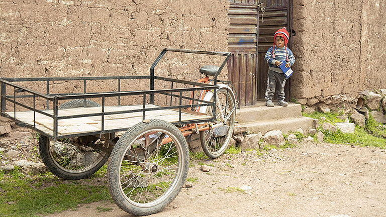 Kind steht neben Fahrrad mit Ladefläche.